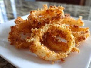 Close-up of a stack of golden-brown, crispy parmesan onion crisps on a white plate.