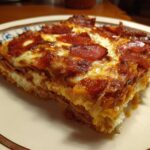 A close-up of a slice of Pizza Cottage Cheese Bake, featuring layers of cottage cheese, sauce, and pepperoni.