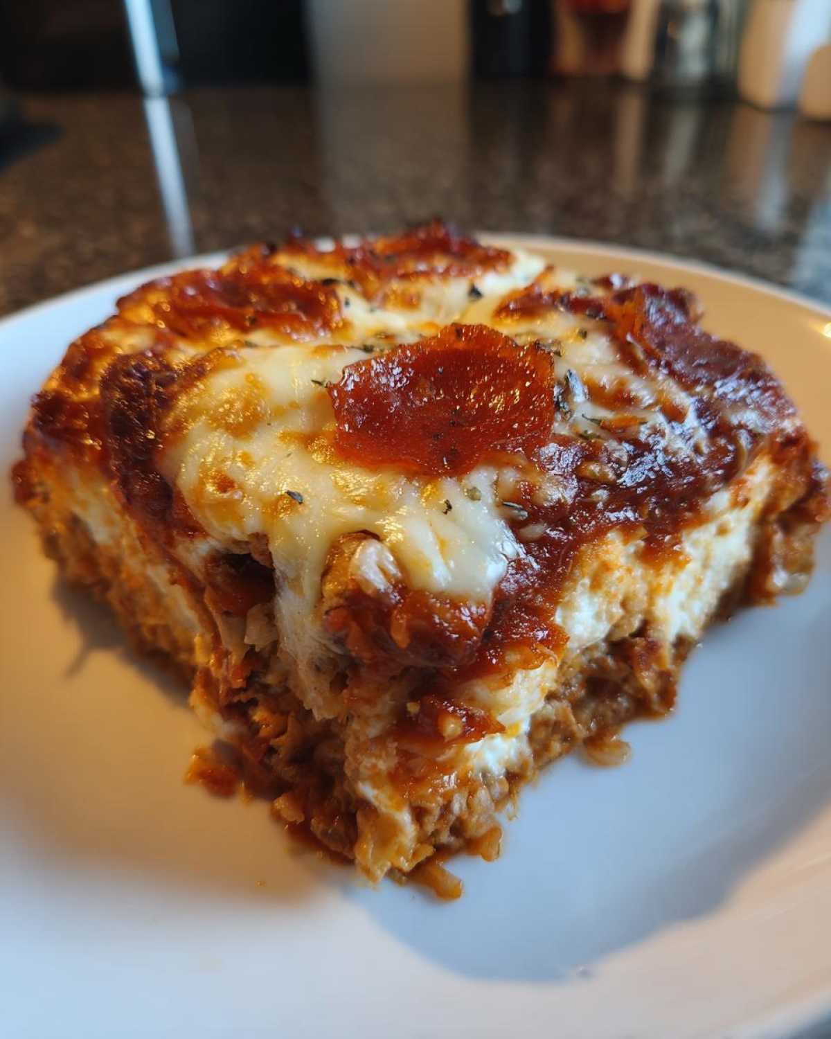 A slice of delicious Pizza Cottage Cheese Bake on a white plate, topped with melted cheese and pepperoni.