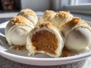 Close-up of white chocolate pumpkin cheesecake truffles, one cut in half to reveal the spiced pumpkin filling and graham cracker crumble.
