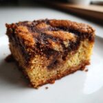 A close-up, macro shot of a single square of snickerdoodle blondies showing the light blondie base swirled with dark cinnamon sugar topping.