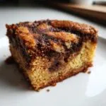 A close-up, macro shot of a single square of snickerdoodle blondies showing the light blondie base swirled with dark cinnamon sugar topping.