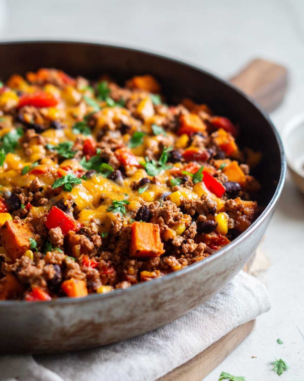 Close-up of a Southwest Turkey Sweet Potato Skillet topped with melted cheese and fresh cilantro.