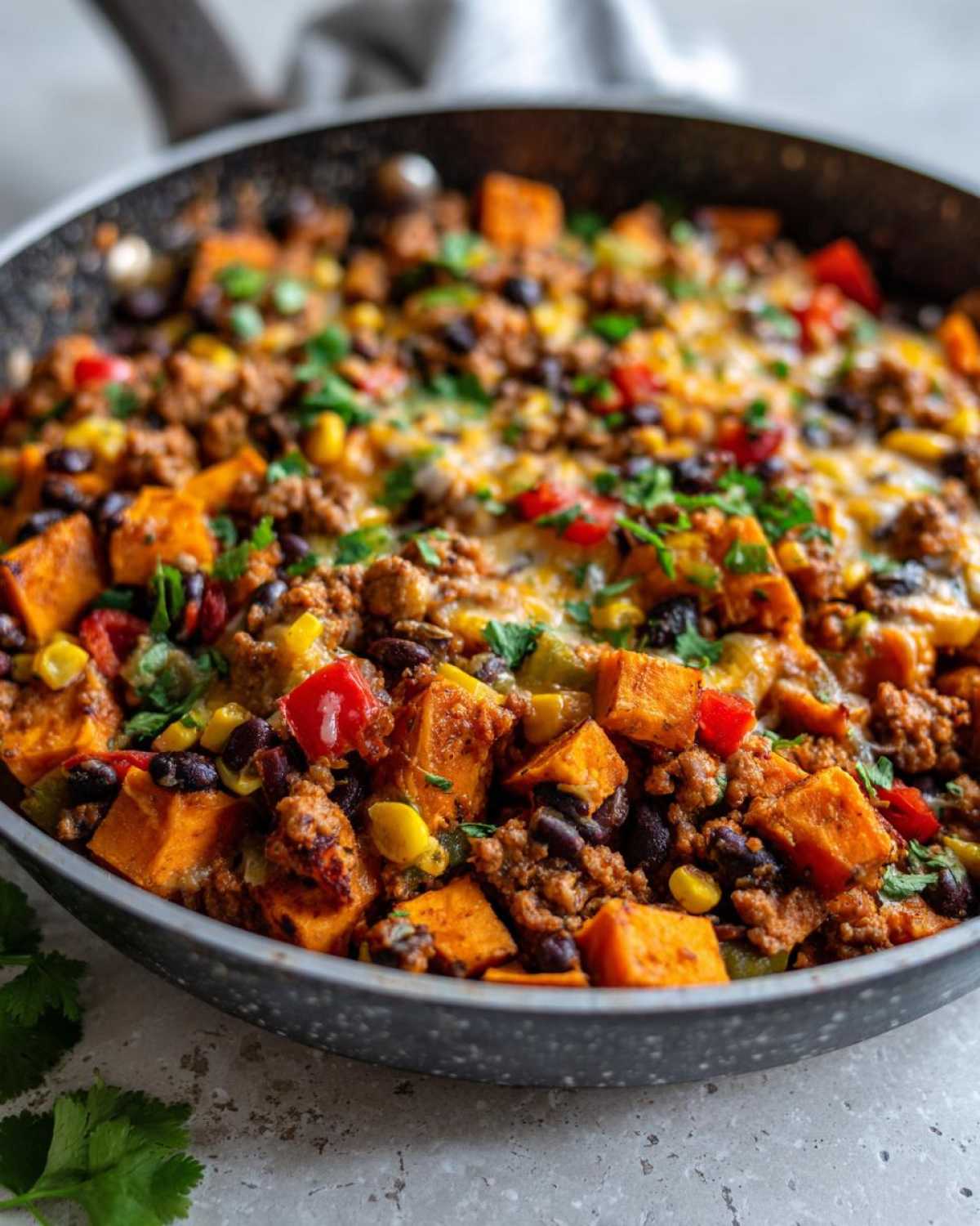 Close-up of a savory Southwest Turkey Sweet Potato Skillet with ground turkey, black beans, corn, and melted cheese.