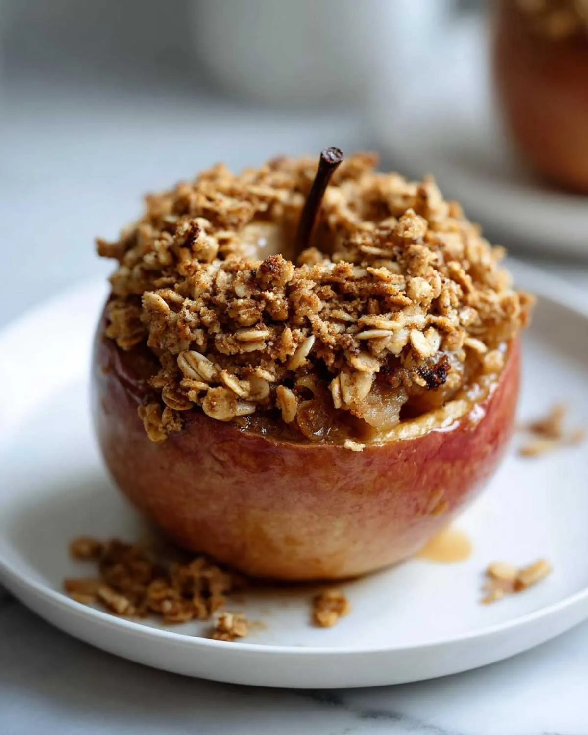 Close-up of a single baked apple stuffed with spiced filling and topped with a crunchy oatmeal crumble.