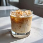 A refreshing Toasted Coconut White Russian cocktail with ice and topped with toasted coconut flakes.