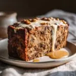 A slice of hearty Vegan Christmas Roast topped with a creamy glaze and walnuts, served on a plate.