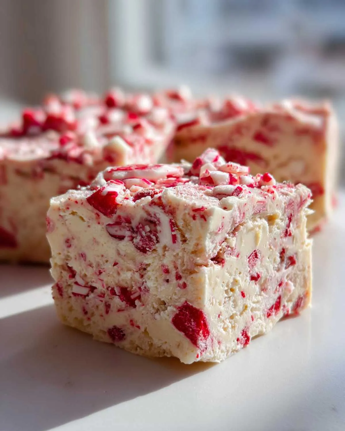 A thick square of creamy white peppermint fudge studded with crushed red and white candy canes.