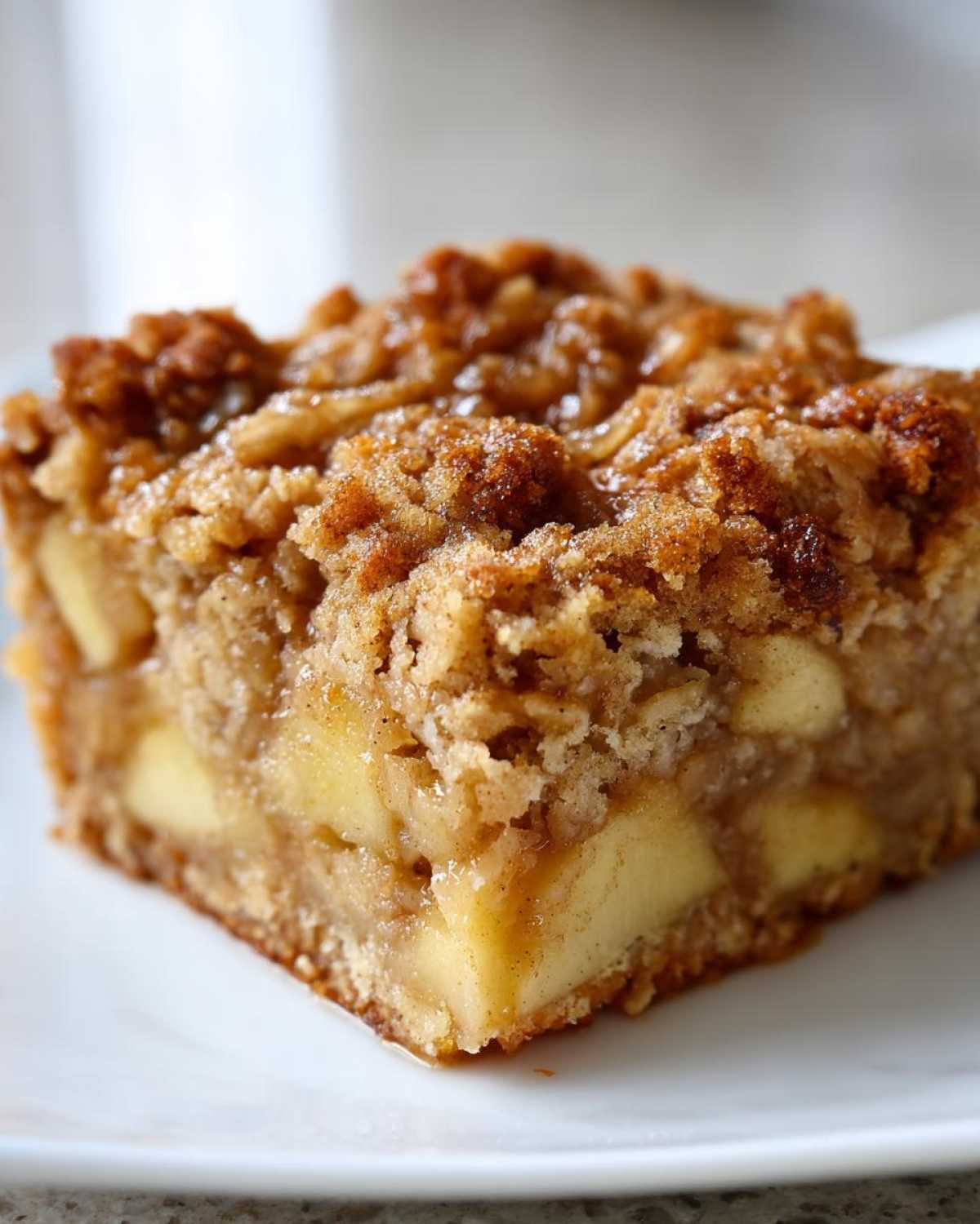 A close-up of a square serving of apple baked oatmeal topped with a cinnamon streusel crumb topping.