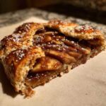 Close-up of a slice of amazing apple galette with caramelized apples and flaky crust sprinkled with coarse sugar.