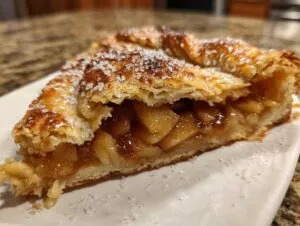 A close-up view of a slice of homemade apple galette showing flaky crust and cinnamon-spiced apple filling.