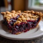 Two decadent slices of blackberry pie featuring a thick, juicy filling and a golden crumb topping.