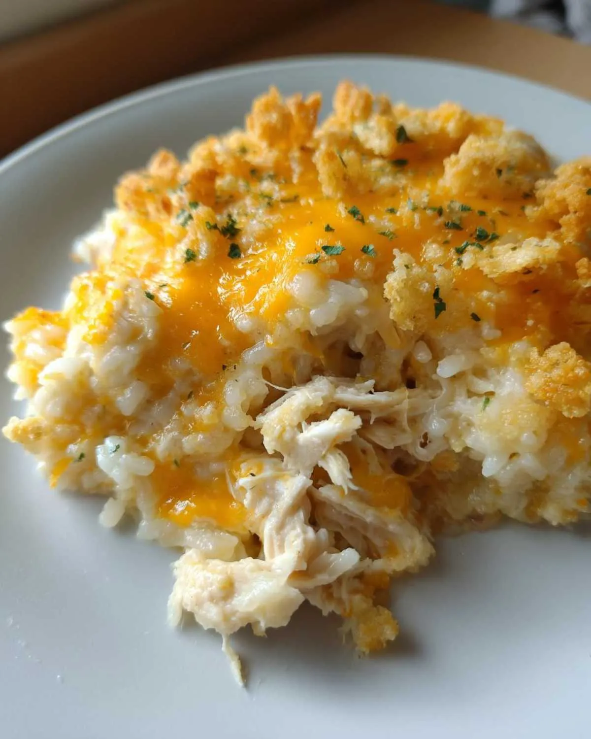 Close-up of a portion of cheesy chicken and rice topped with melted cheddar and crunchy breadcrumbs.