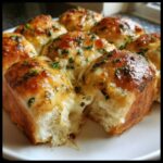 Close-up of cheesy hawaiian roll garlic bread, showing melted cheese stretching as a roll is pulled apart.