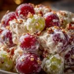 Close-up of creamy Chicken Salad Chick Grape Salad featuring red and green grapes coated in dressing and topped with chopped pecans.