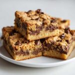 A stack of thick, chewy chocolate chip cake mix cookie bars with melted chocolate swirls.