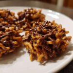 Close-up of three homemade haystack cookies made with chow mein noodles and drizzled with melted chocolate.