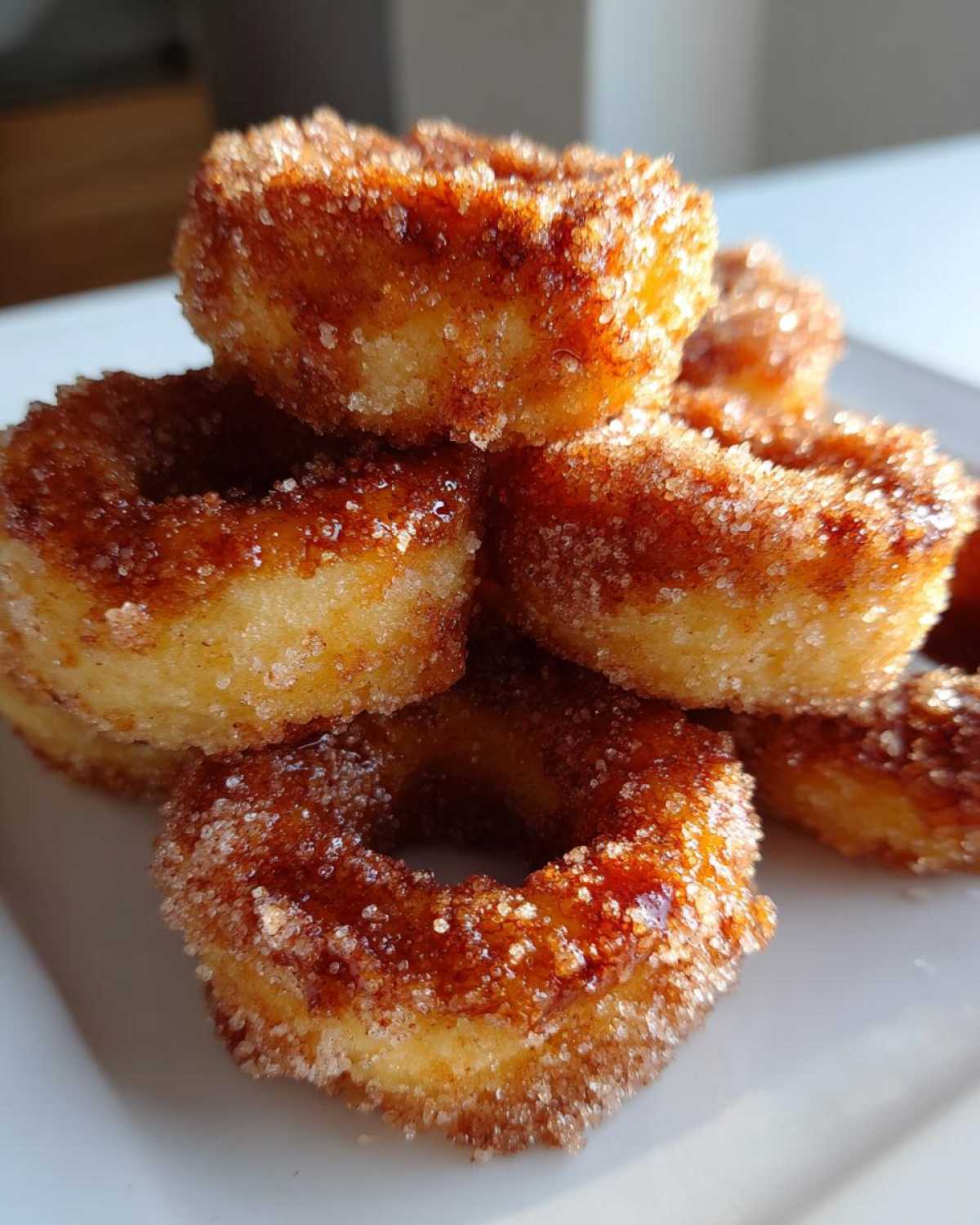 A close-up stack of homemade mini donuts coated heavily in sparkling cinnamon sugar.