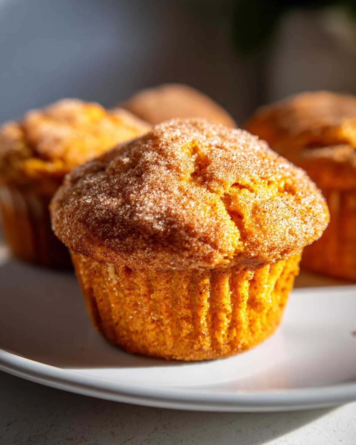 A close-up of a freshly baked sweet potato muffin topped generously with cinnamon sugar.