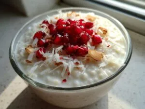 Close-up of creamy coconut chia pudding topped with bright red pomegranate seeds and shredded coconut.