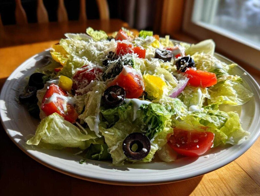 A vibrant plate of copycat Olive Garden salad featuring crisp lettuce, tomatoes, olives, and grated cheese.
