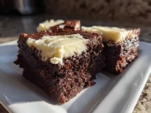 Close-up of rich, dark gingerbread brownies topped with a layer of creamy white frosting.