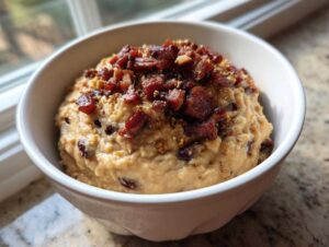 A white bowl filled with creamy black eyed peas mash, topped generously with crispy bacon bits.