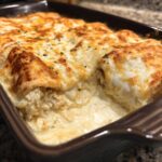 Close-up of creamy white sauce chicken enchiladas baked until golden brown and bubbly.