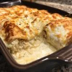 Close-up of creamy white sauce chicken enchiladas baked until golden brown and bubbly.