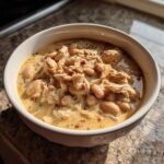 A close-up of a bowl filled with creamy white chicken chili, featuring shredded white chicken and white beans.