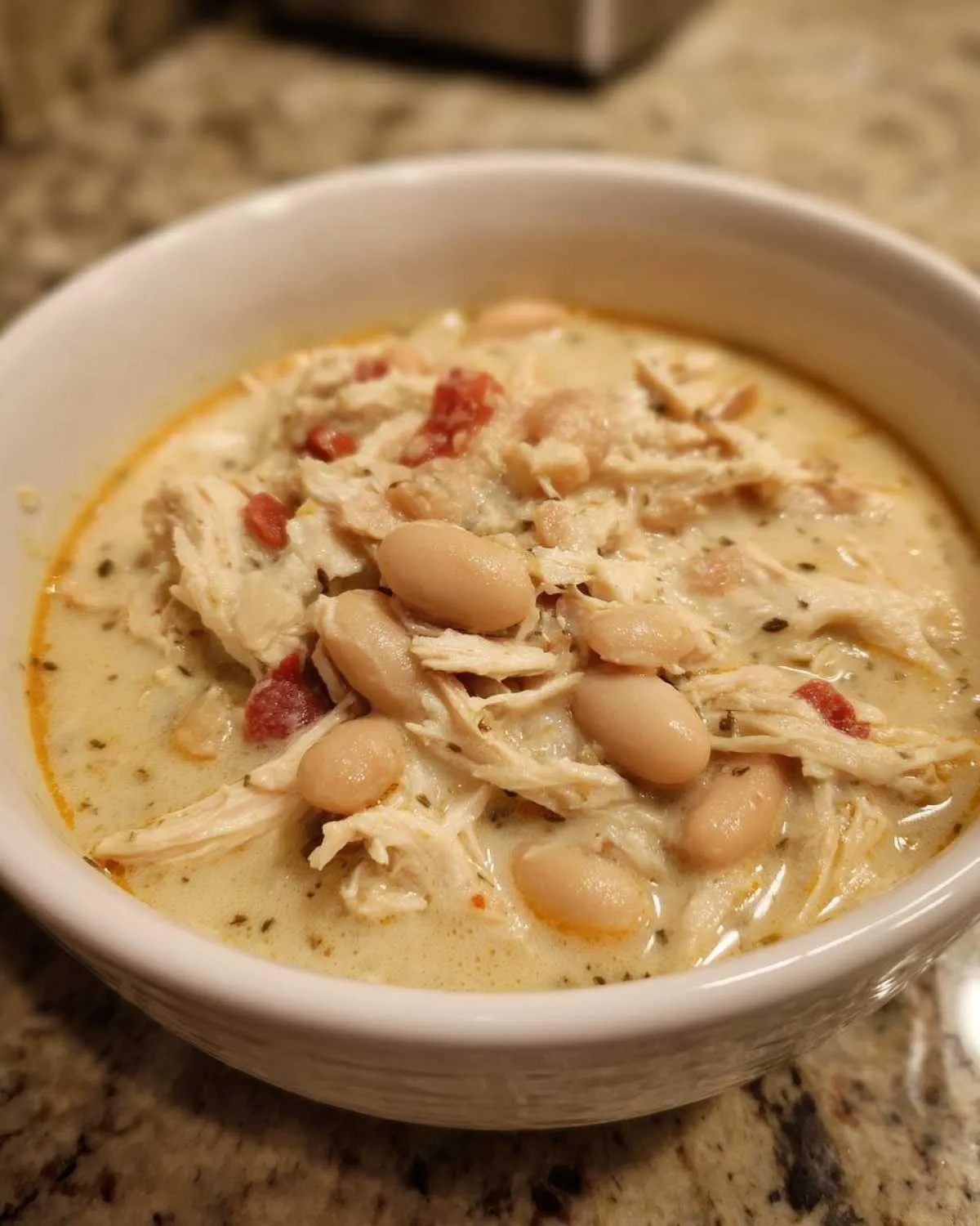Close-up of a bowl of creamy white chicken chili featuring shredded white chicken and cannellini beans.
