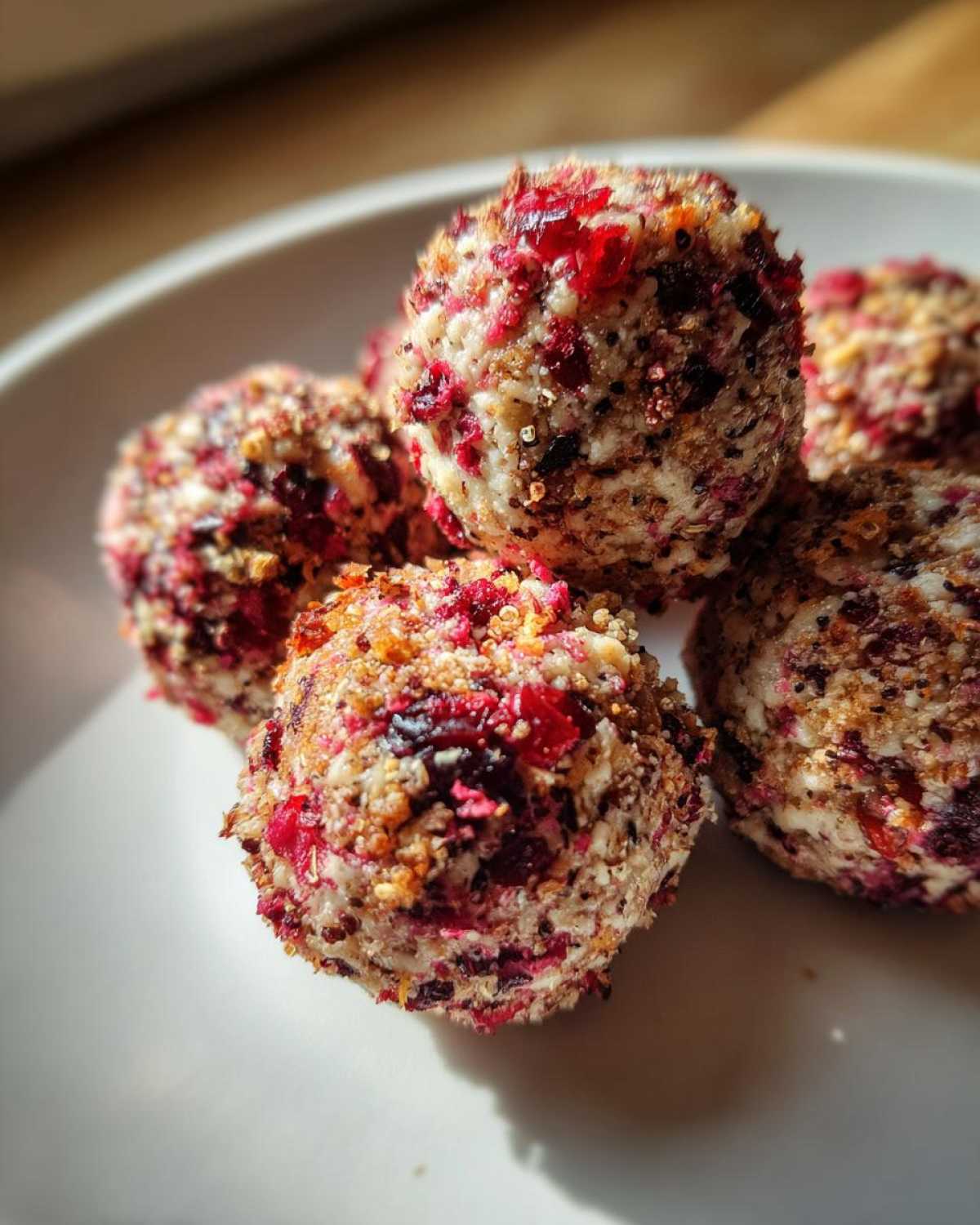 A close-up of several homemade goat cheese balls coated in crushed nuts and bright red dried fruit pieces.
