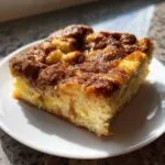 A square slice of fluffy baked french toast topped with a rich, gooey cinnamon-sugar glaze.