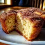 A french toast muffin broken in half showing the soft, fluffy interior and a thick cinnamon sugar topping.