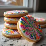 A stack of sugar cookies topped with glossy white cookie icing featuring a vibrant, wet-look rainbow swirl design.