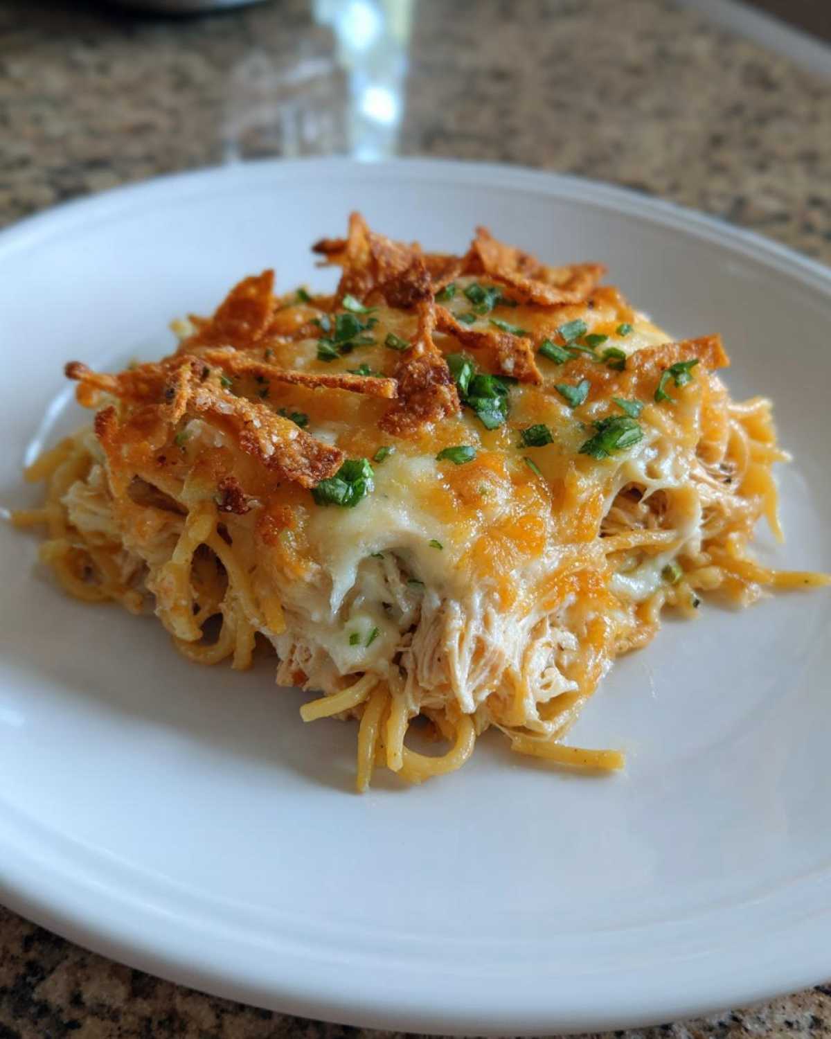 A square portion of Monterey Chicken Spaghetti covered in melted cheese and crispy topping.
