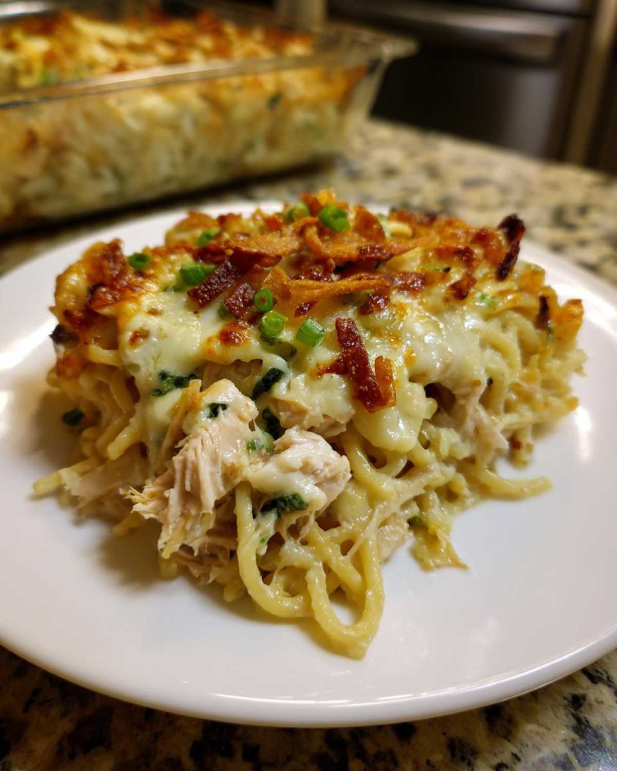 A close-up serving of creamy Monterey chicken spaghetti topped with melted cheese and crispy onions.
