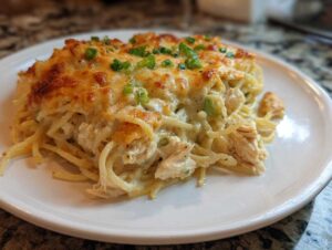 A close-up serving of creamy Monterey chicken spaghetti topped with melted, browned cheese and green onions.