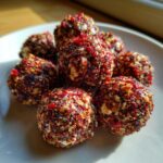 A cluster of homemade goat cheese balls coated in a vibrant red, crunchy nut and spice mixture.