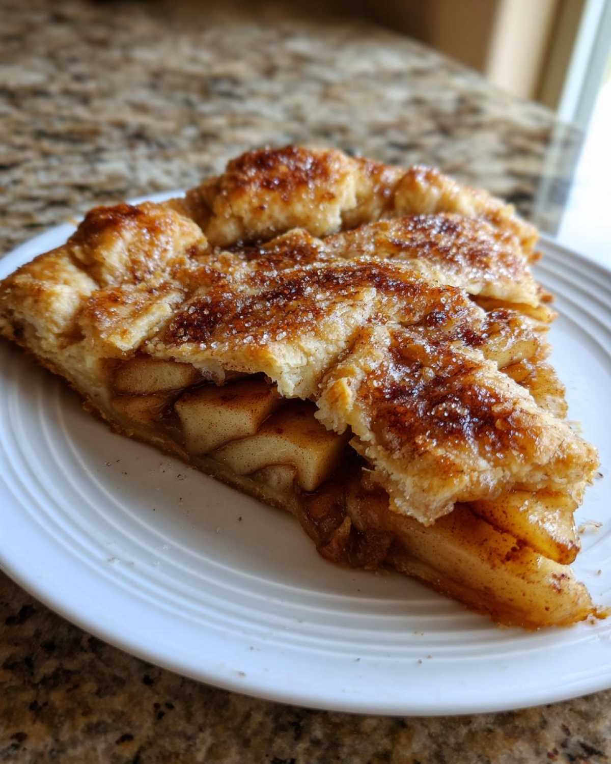 Close-up of a delicious slice of apple galette showing flaky crust and cinnamon-sugar topping.