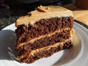 Close-up of a rich, dark slice of gingerbread latte cake with two layers of light brown frosting.