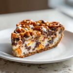 A decadent slice of texas trash pie featuring a creamy filling loaded with chocolate chips, topped with pretzels and caramel.