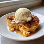 A warm slice of snickerdoodle cobbler topped with melted cinnamon sauce and a scoop of vanilla ice cream.