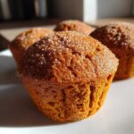 A close-up, sunlit view of freshly baked sweet potato muffins topped generously with sparkling granulated sugar.