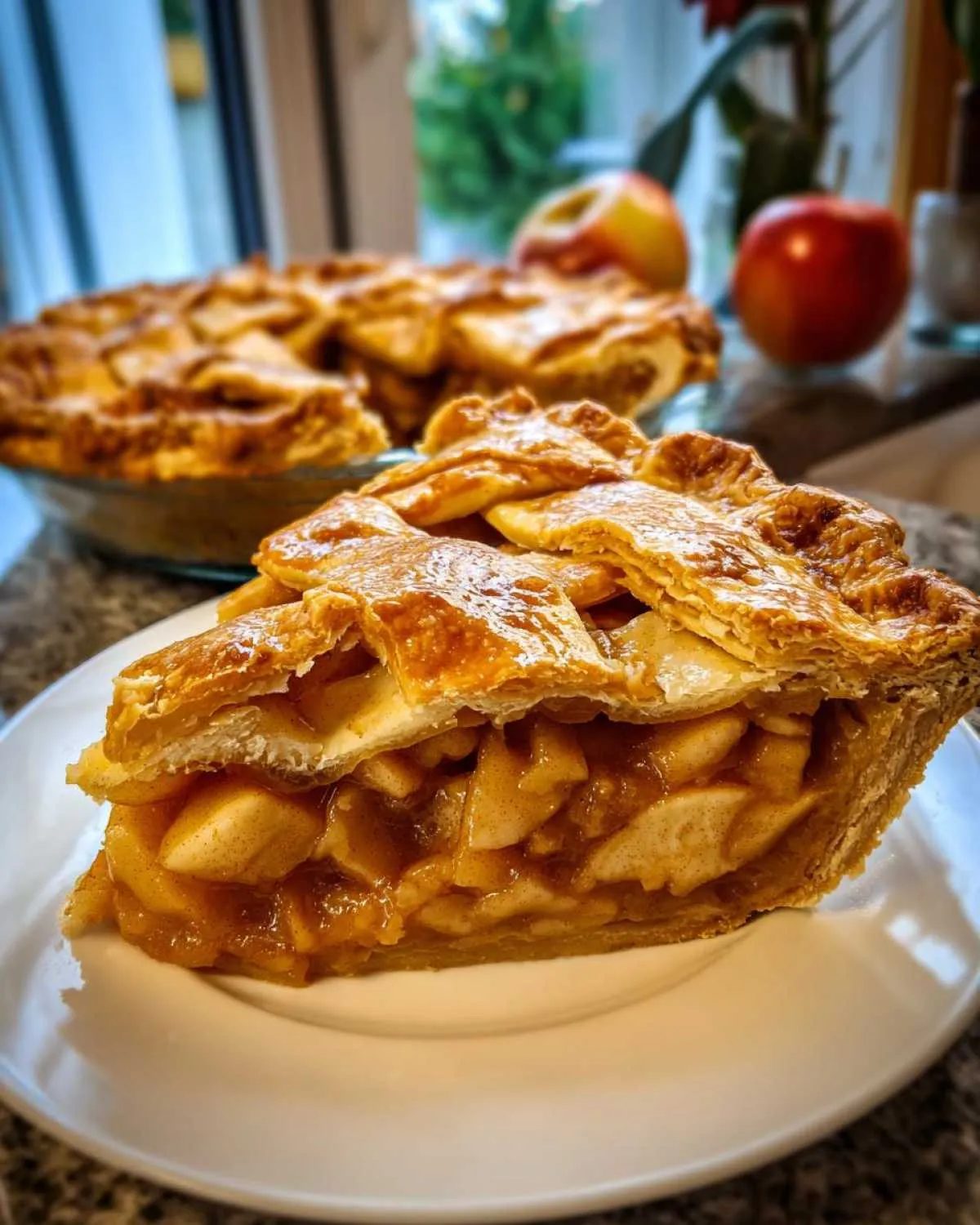 Close-up of a thick slice of apple pie recipe showing flaky crust and cinnamon-spiced apple filling.