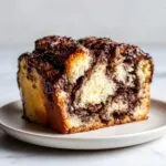 Close-up of a moist slice of chocolate babka showing rich swirls of filling and a glossy chocolate drizzle.