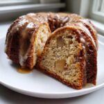 Close-up of a slice cut from an apple bundt cake, drizzled with a thick caramel glaze.