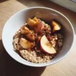 A close-up of warm apple cinnamon oatmeal topped with caramelized apple slices and cinnamon sugar.