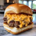 Close-up of a delicious burger patty smothered in creamy, orange big mac sauce on a toasted bun.