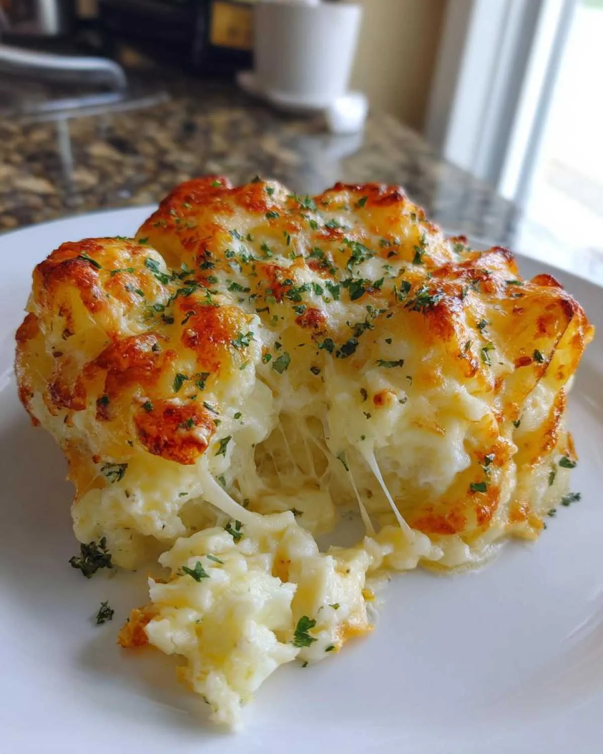 Close-up of a serving of cheesy potato casserole showing a dramatic cheese pull and golden-brown topping.